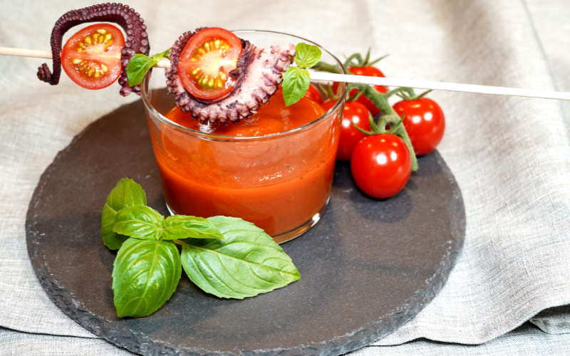 Oktopus-Stücke am Spieß zu Tomaten-Kokos-Suppe